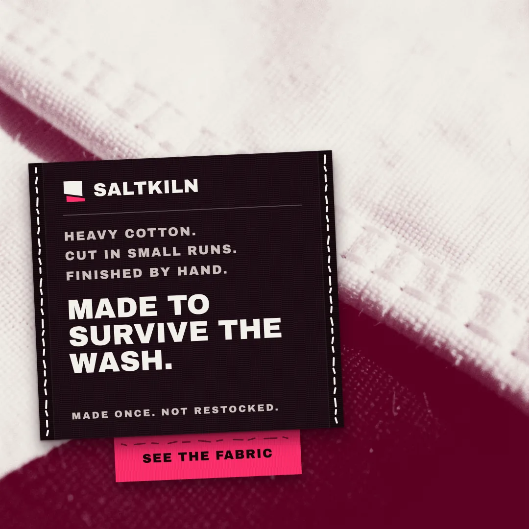A SALTKILN ad with a black care label on heavy white and maroon cotton that reads Made to survive the wash.